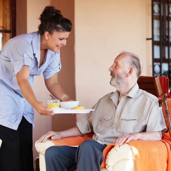 Carer serving food to the elderly man