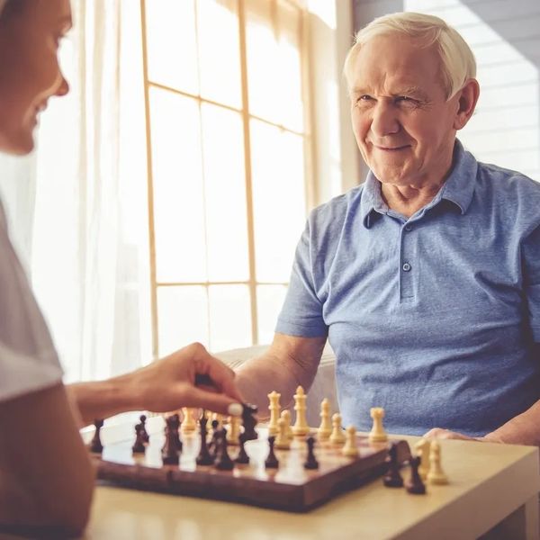 Carer playing chess with an elderly man