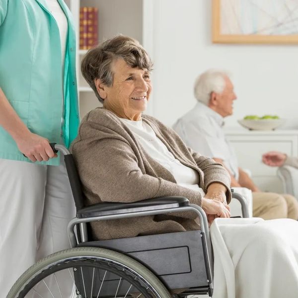Elderly woman assisted by a carer in a wheelchair