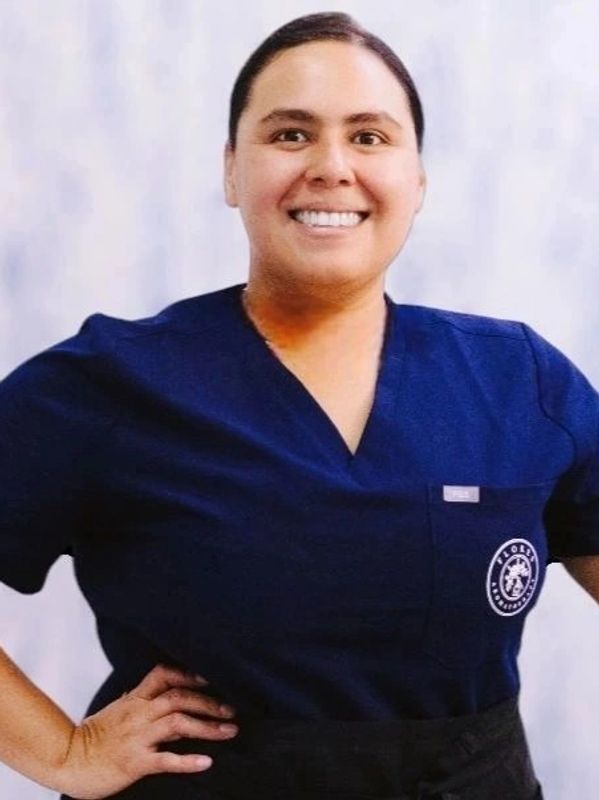 Smiling healthcare professional in navy blue scrubs posing confidently.