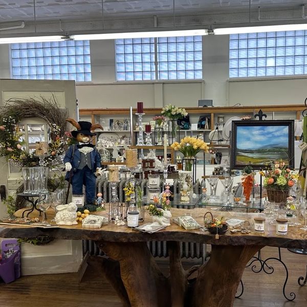 Decorative display table with various items and a dressed rabbit figure.