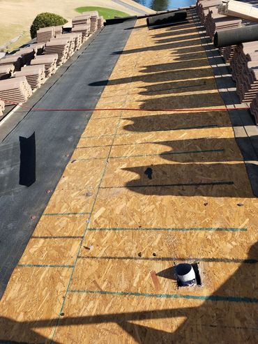 Roof under construction with stacked tiles and plywood base.