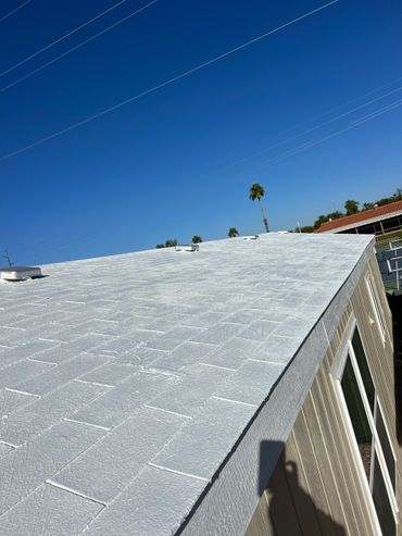 White rooftop of a building under clear blue sky with palm trees in the background.