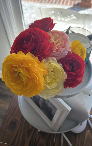 A vibrant bouquet of red, yellow, and pink flowers in a glass vase.