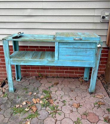 Rustic blue wooden outdoor cooler with bottle opener and shelf.