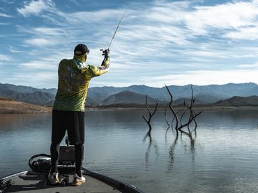 Pescatore in azione su lago montano durante un'uscita outdoor.