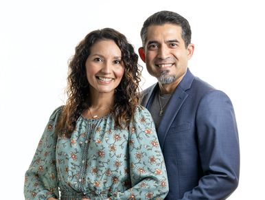 Smiling couple posing together against a white background.