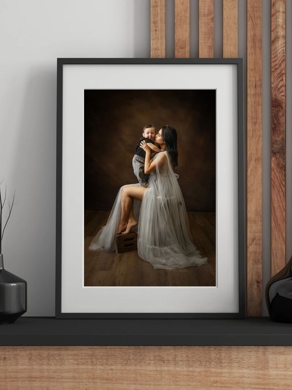 Elegant photo of a woman in a flowing dress holding and kissing a baby.