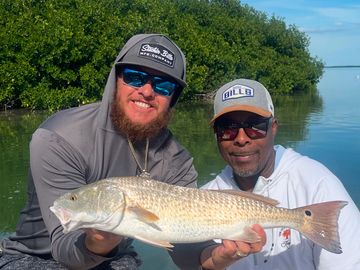 Two men on a boat proudly holding a large fish they caught.