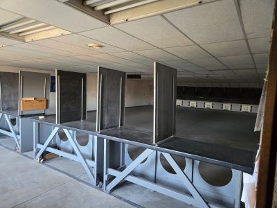 Empty indoor shooting range with multiple firing lanes and dividers.