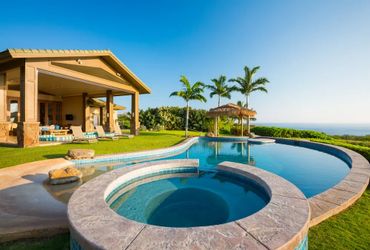 Luxurious outdoor pool and spa with ocean view by a modern house.