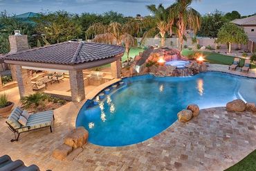 Luxurious backyard pool with a hot tub and covered lounge area.
