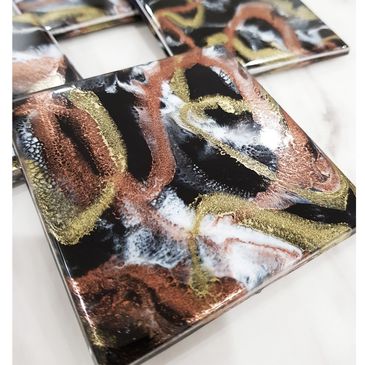 set of 4 coasters. colours are black gold copper and white.