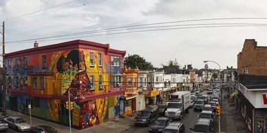Image of a colorful mural on the side of a building with cars on the street around it.
