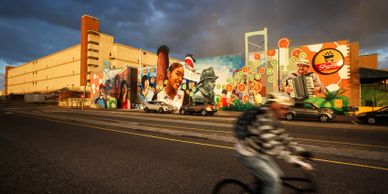 Image shows a biker riding in front of a mural in South Philadelphia.