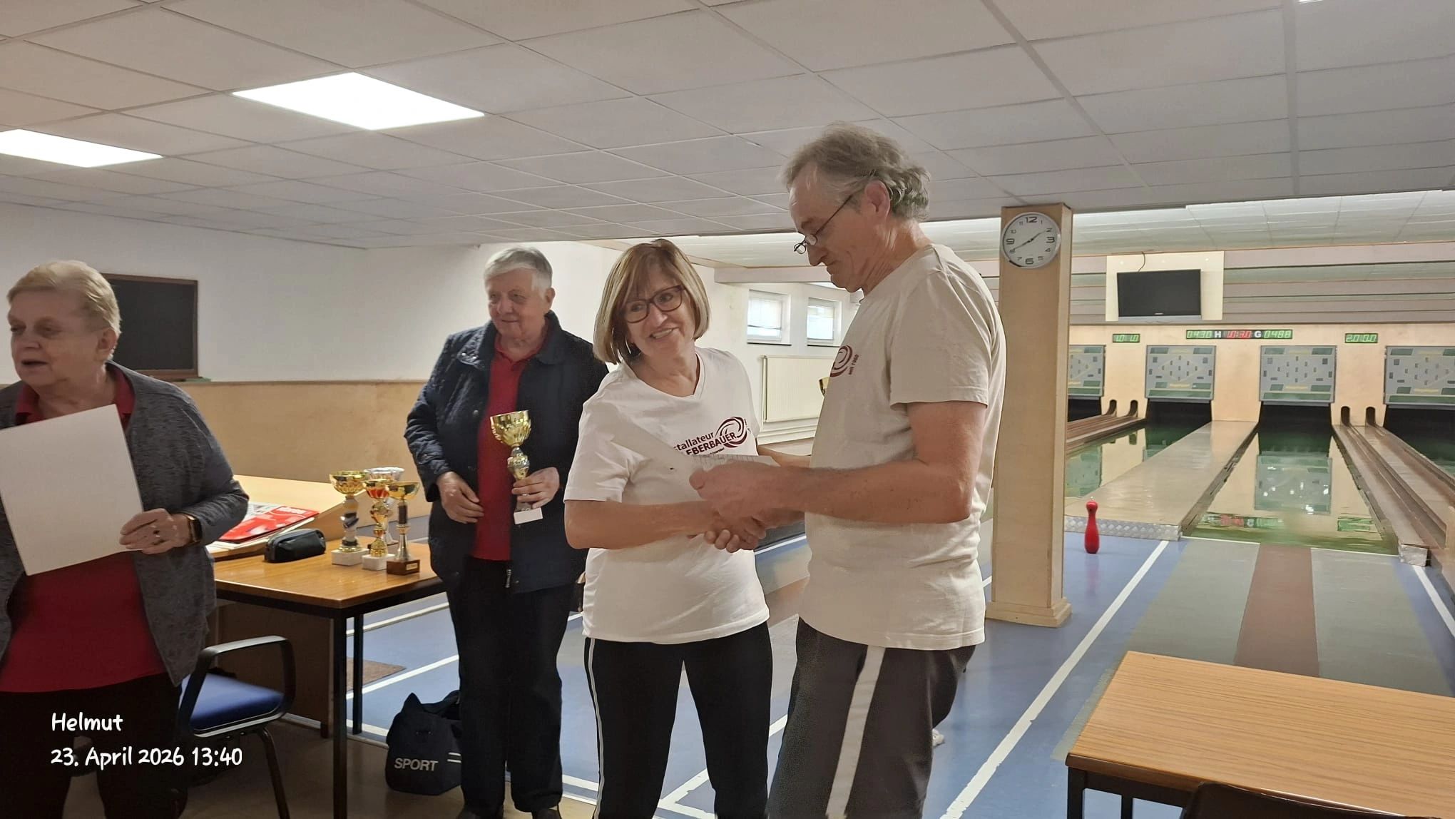 People exchanging awards in a bowling alley setting.