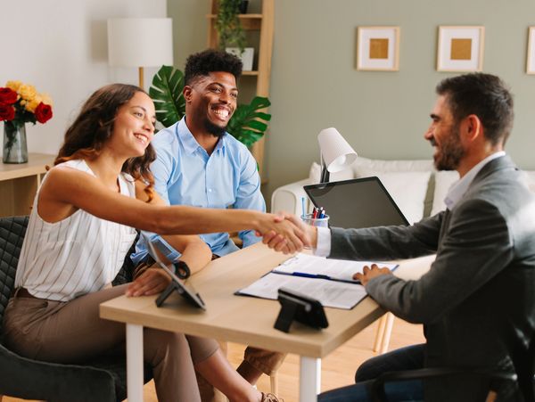 Young Latin American couple makes a deal with an agent in the office and does handshake