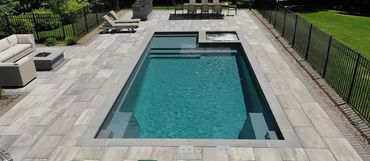 Modern backyard pool with lounge chairs and dining area.