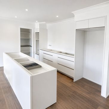 Modern white kitchen cabinets and island with wood flooring.