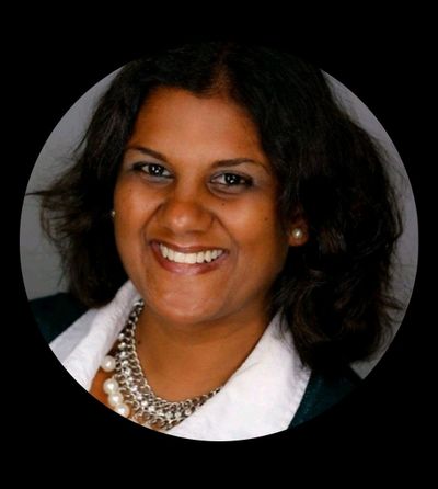 Smiling woman with dark hair and pearl necklace in a professional portrait.