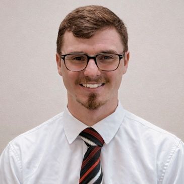 A smiling man in glasses and a striped tie.