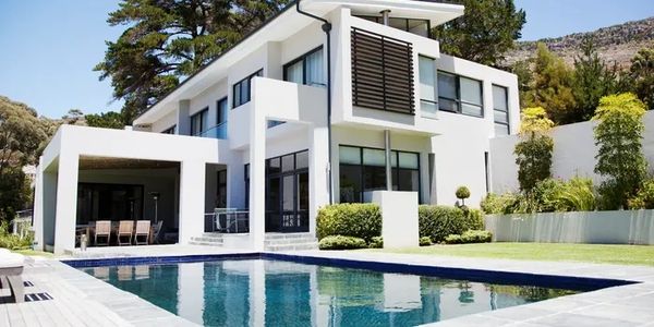Modern white two-story house with a spacious pool and patio area.