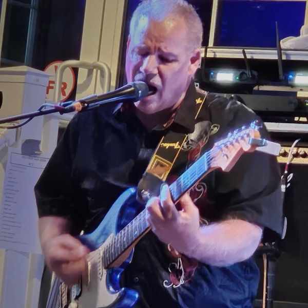 Man passionately singing and playing guitar on stage.