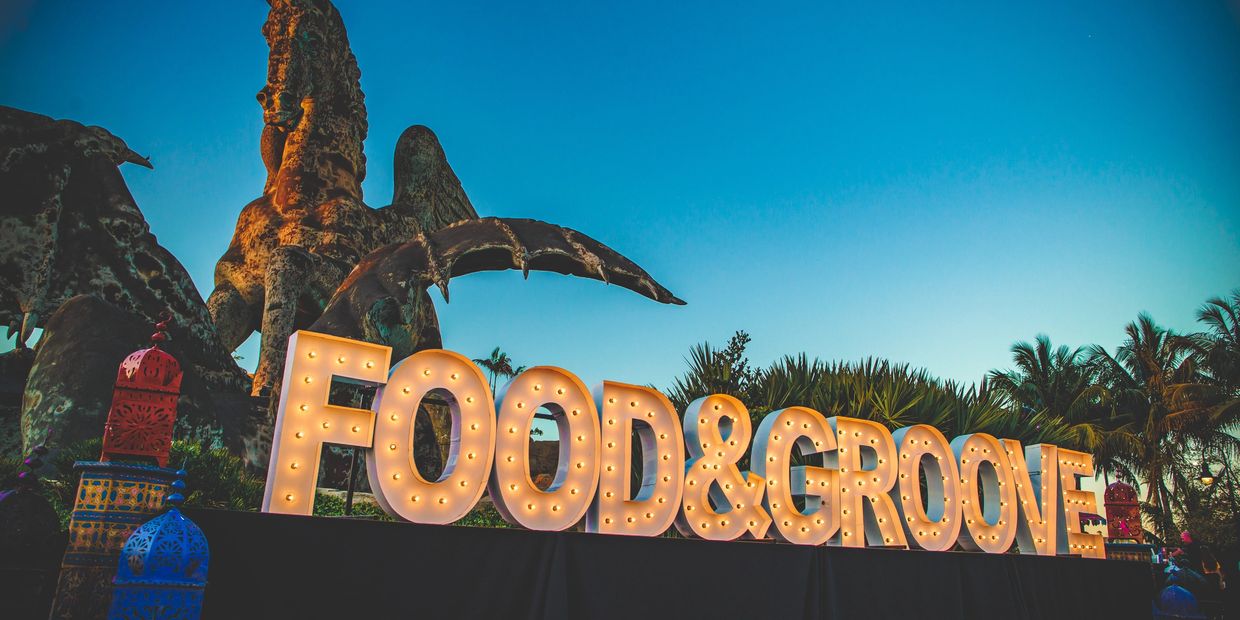A block-letter sign with lights in the middle of each letter spells out "Food & Groove". The sky is 