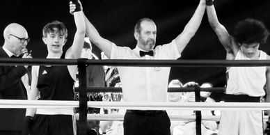 Referee raising the winner's hand after a boxing match.