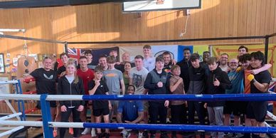Group of young athletes posing inside a boxing ring.