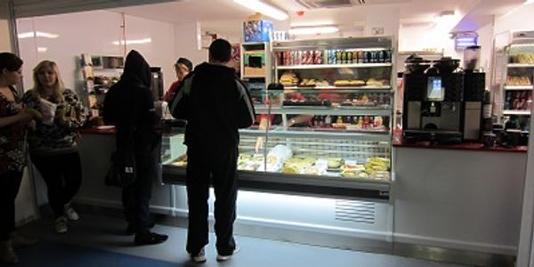 Students at a take-away snack bar with refrigerated display, servery & hot drinks machine by  a till