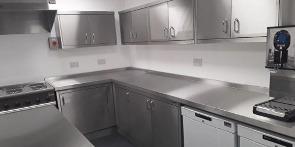 Clean stainless steel wall and floor cupboards, refrigerator, cooker and hot drinks machine. 
