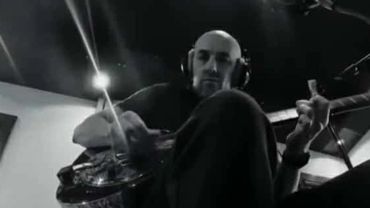 Man playing guitar in a recording studio wearing headphones.