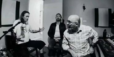 Three men in a recording studio having a discussion.