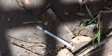 Discarded needles and syringes lie near a wall bordering a Phnom Penh hospital. (Matt Surrusco)