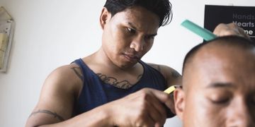 Soeun Chheng gives a haircut to another Cambodian deportee Sarim Khleung in Phnom Penh. Emil Kastrup