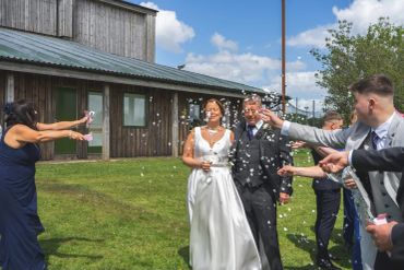 Newlyweds walking as guests throw confetti.