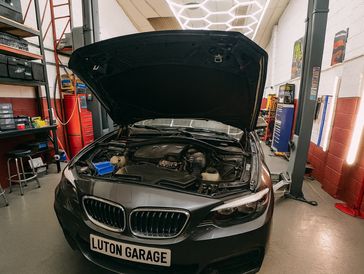 BMW car with open hood inside a garage named Luton Garage.