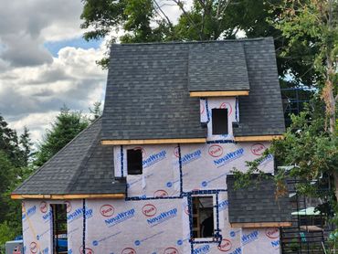 A house under construction with dark shingle roofing and NovaWrap weather barrier.