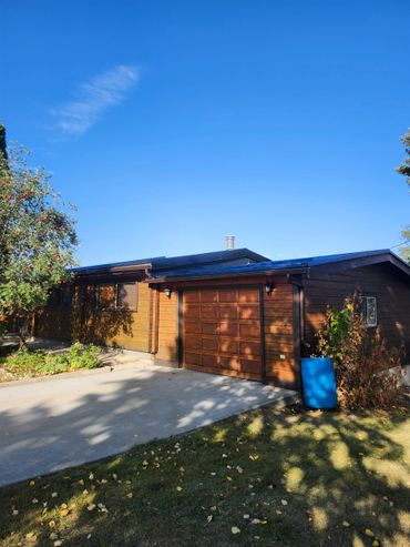 Wooden house with a garage under a clear blue sky.