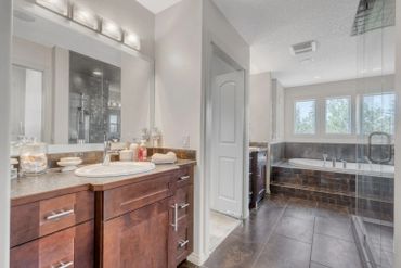 Modern bathroom with dark wood cabinets and tiled floors.