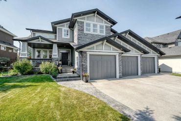 Modern two-story house with a three-car garage and well-maintained lawn.