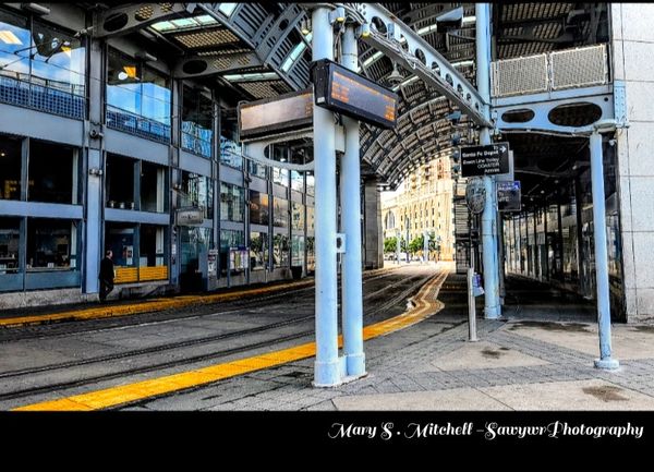 Empty urban tram station with modern architecture and reflective glass walls.