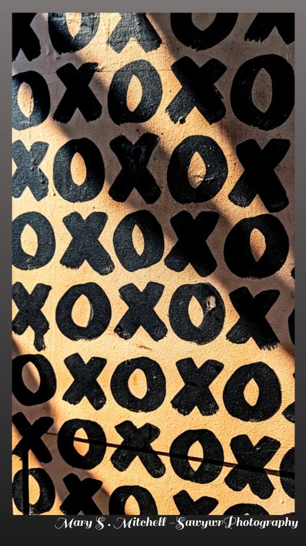 Black 'X' and 'O' patterns painted on a beige wall.