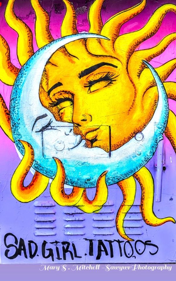 Vibrant mural of sun and moon with faces, symbolizing contrast and unity.