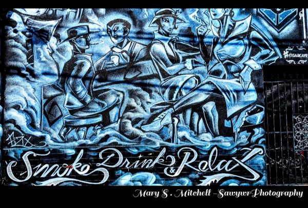 Blue-toned mural of stylish figures with the words 'Smoke Drink Relax'.