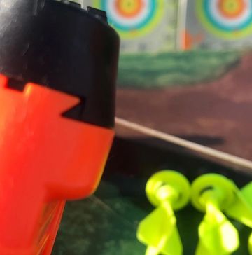 Close-up of an orange dart gun with yellow darts in the background.
