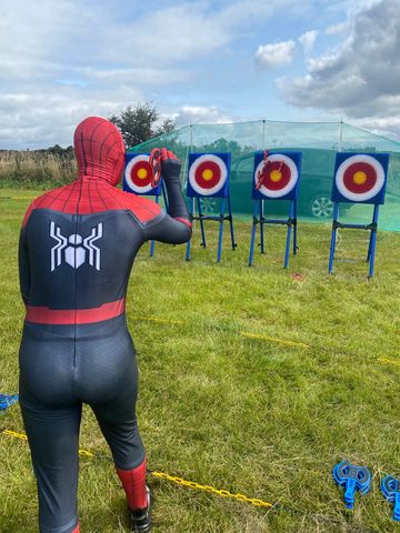 Person in Spider-Man suit aiming at archery targets.