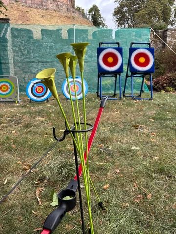 Archery practice setup with bows, arrows, and targets outdoors.