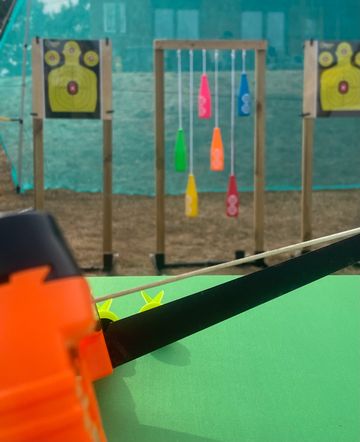 Arrow pointing towards colorful hanging targets at an archery range.